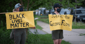 On May 26, 2020, people protested against police violence after the death of George Floyd. Two protesters, one with a Black Lives Matter sign and the other with a Justice for George Floyd sign. (Photo by Fibonacci Blue/Wikimedia Commons)