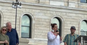 Lt. Gov. Peggy Flanagan speaks at the Thousands took part in the Our Future: March for Abortion Access rally at the Capitol on July 17, with First Lady Gwen Walz and Gov. Tim Walz (left), and Flanagan's husband Tom Weber (right).