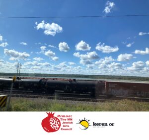 Photo of a Canadian Railway train under a bright blue sky with many individual spots of clouds.