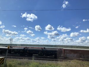 Photo of a Canadian Railway train under a bright blue sky with many individual spots of clouds.