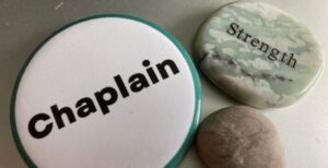 The "chaplain" button was worn by Rabbi Liberman in Pittsburgh. The stone that reads "strength" is one of the self-care stones available for survivors to hold. The small stone is Rabbi Liberman's, which she kept in her pocket for her own self-care.