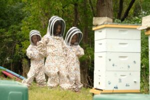 Dena Fink, Maytal Ribnick and Thea Fink wear protective bee suits to get close to the hives in Jenifer Robins backyard. (Photo by Lev Gringauz/TC Jewfolk)