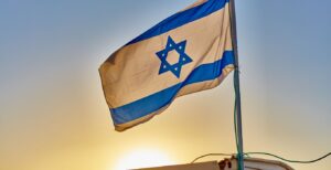 Israeli flag with sun setting behind it.