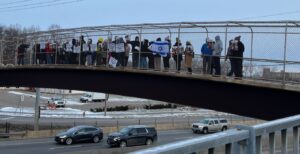 Dozens of people on the pedestrian bridge over Highway 100 to bring awareness of the hostages still in Gaza. (Photo by Lonny Goldsmith/TC Jewfolk).