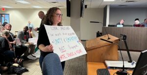 Mirit Avny holds a sign at the Feb. 8 Minneapolis City Council meeting. The sign reads "Look Around: Your work should promote Unity & Empathy, not propagate Hate, divide & Fear."