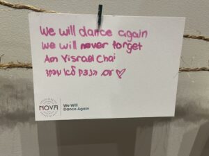 A card written by a visitor to the Nova Music Festival exhibit in New York. The card reads: "We will dance again.We will never forget. Am Yisrael Chai." The last line repeated in Hebrew. (Jeff Mandell for TC Jewfolk).