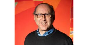 headshot of Ken Agranoff in front of red and orange art piece.